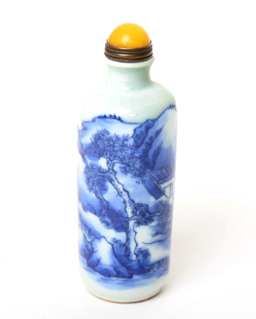 Chinese Blue & White Snuff Bottle: Chinese blue and white porcelain painted snuff bottle with a yellow cabochon affixed to the stopper with a metal spoon. Scrolling landscapes throughout the tall bodied bottle. Seal mark to the base. S