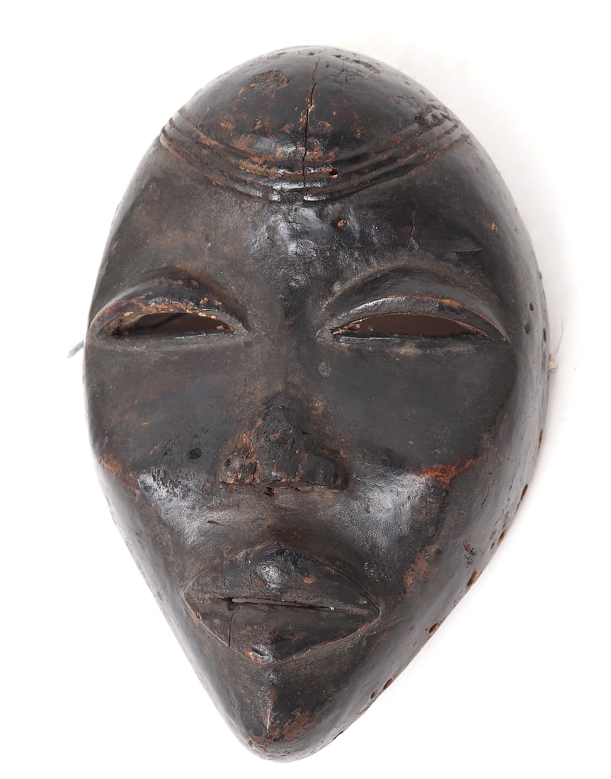 African Carved Wood Dan Mask: Africa, Ivory Coast / Liberia, African Dan peoples mask. Heavy patina to surface with pierced eyes and mouth. The reverse with a worn finish to the interior. Outer perimeter of the reverse is pierced 