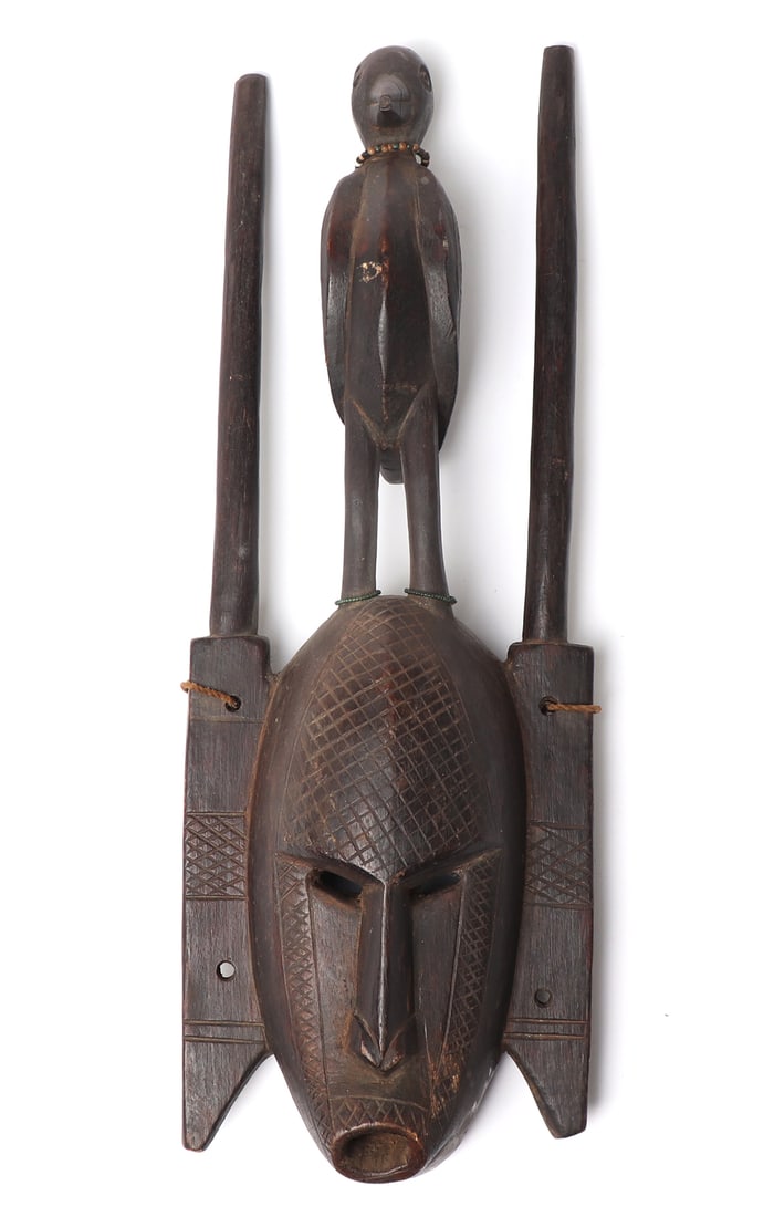 African Wood Carved Face Mask w/Bird: Handsomely carved wood African mask with bird finial, likely Bamana culture. Scarification throughout the face, protruding elongated nose and pierced eyes. The bird stands atop his head with incised f