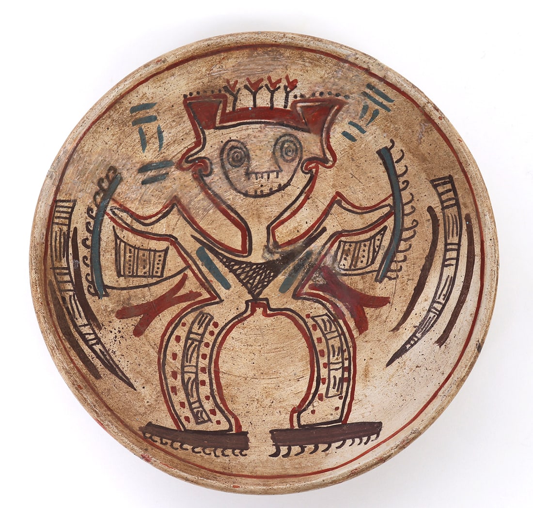 Cocle Style Polychrome Pottery Plate: Panama, stylistically circa 1000 AD. Shallow polychrome painted plate with a figural human painted to the face. Figure wears a bird like feather cloak with elaborately details pants standing on pegged