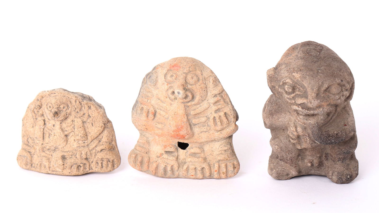 Tumaco La Tolita Pottery Figural Whistles Lot: Ecuador circa 300 BC-300 AD buff and grey clay whistles. Hand molded figural whistles, including two zoomorphic creatures in buff clay, and a hunched man in grey with an expressive face. Each wonderfu