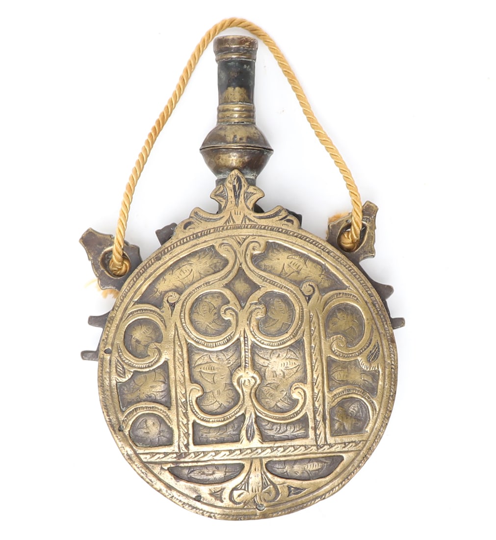 Islamic Brass Engraved Powder Flask, 19th c.: Islamic brass round powder flask, 19th century. Probably Morocco, the reverse with embossed engraved scrolling and floral motifs. The face with a well embossed panel and chased engraving. Size 7" H x4