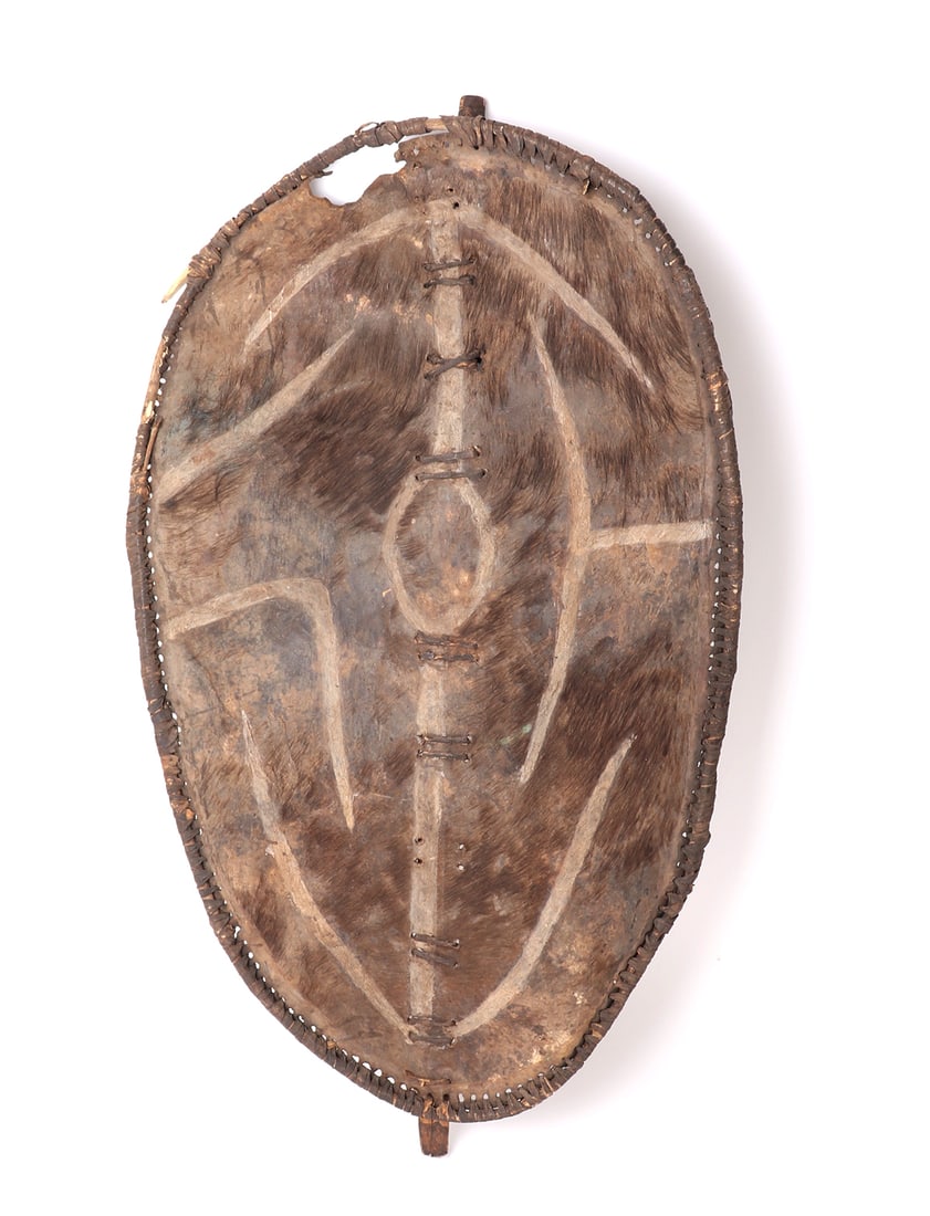 African Okumba Shield, Luo Peoples Circa 1950s or Later: Africa, Kenya, Luo peoples circa 1950s or later Okumba shield of hide, pigment, and wood. The shield if ovoid form and wrapped tightly to the border. The raw hide face retains some fur and is decorate