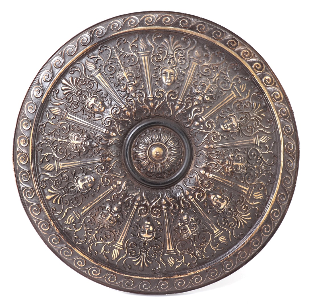 Decorative Embossed Shield: Very ornate and decorative renaissance style shield from an old prop house. The face with beautiful relief depictions of renaissance faces between flaming columns and a central rondel. Size 16" L x 16