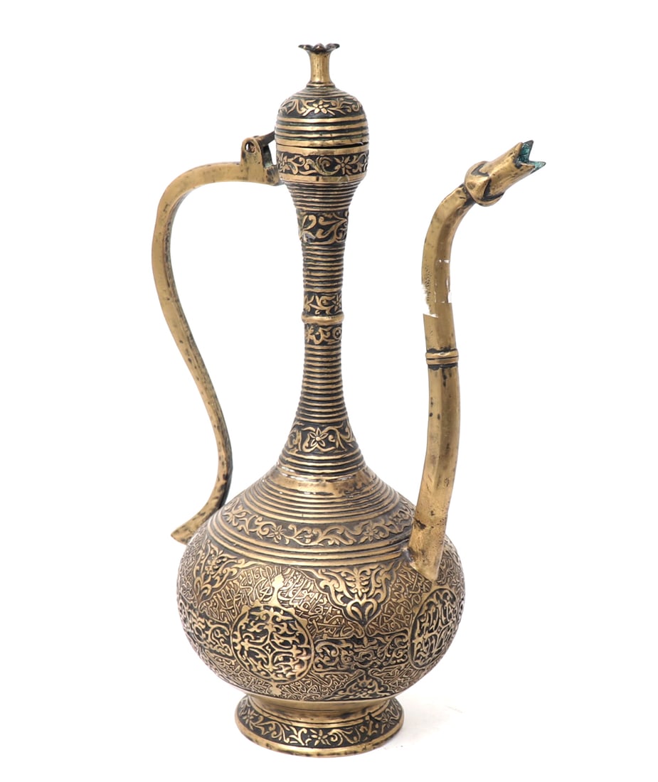 Indo-Persian Brass Elongated Ewer: Indo-Persian ornate and very elongated slender brass ewer. Covered in incised decoration with numerous bands to the background of the decoration in Islamic script. Metal displays pitting due to age. R