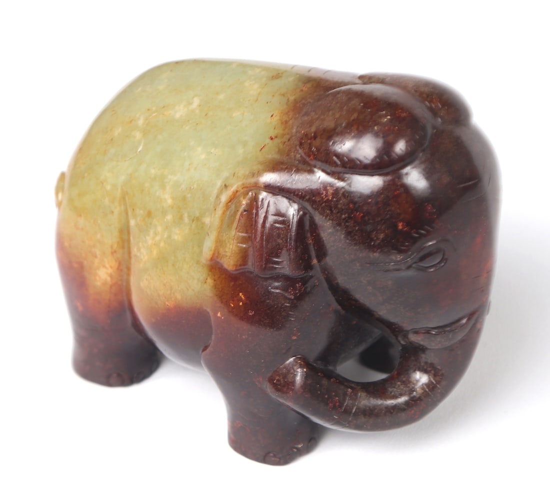 Chinese Elephant Carving, Late Qing Dynasty 1644-1912: Chinese elephant carving depicting a heavy elephant in a Haitian jade and brown stone with light detailing throughout. The Chinese jade elephant is a powerful and multi-faceted symbol that resonates