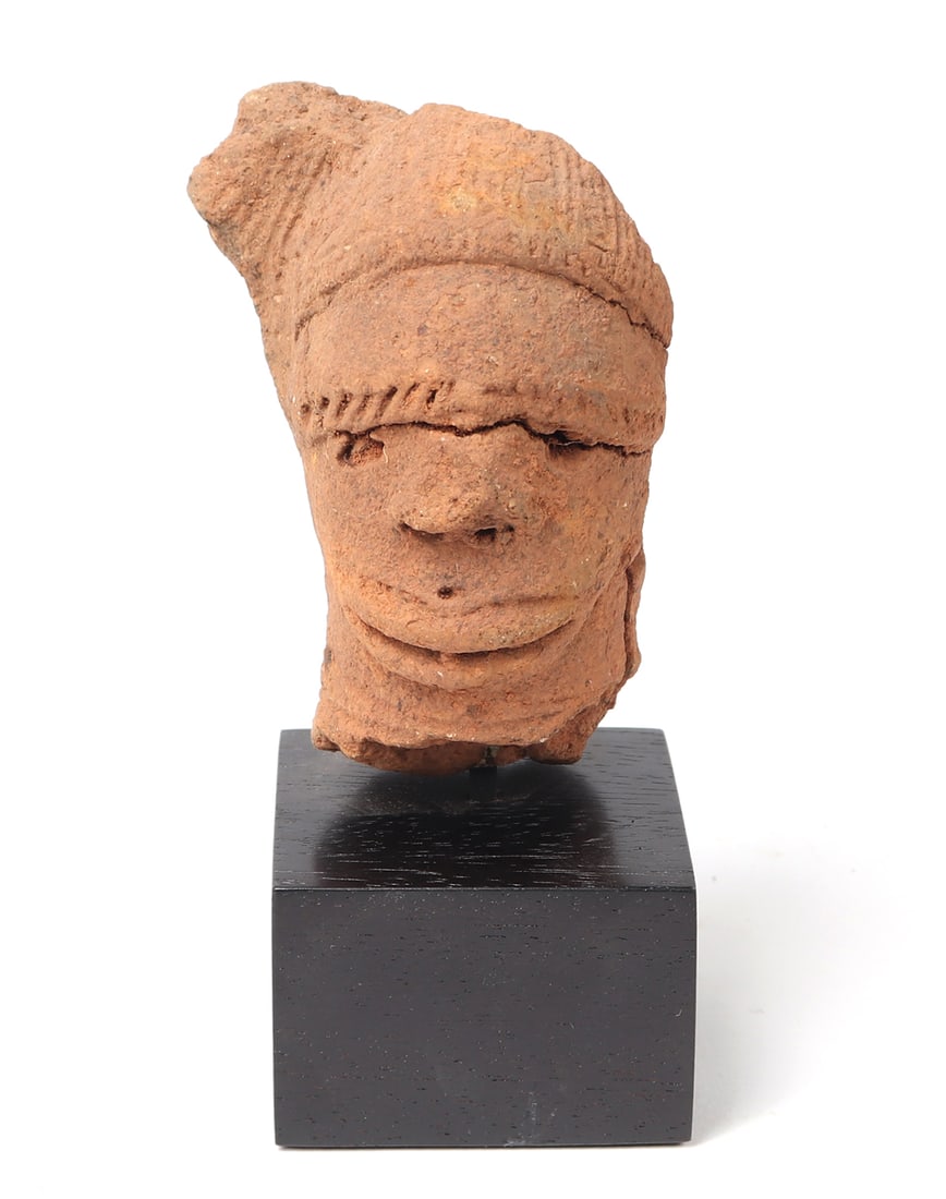 Ancient Nok Terracotta Head, 500 BCE-500 CE: Terracotta head of a male figure with hat and wide brow. Nok figures and the discovery of the culture circa 1928 has indicated the remains of the Nok civilization once span a large area of Nigeria, N