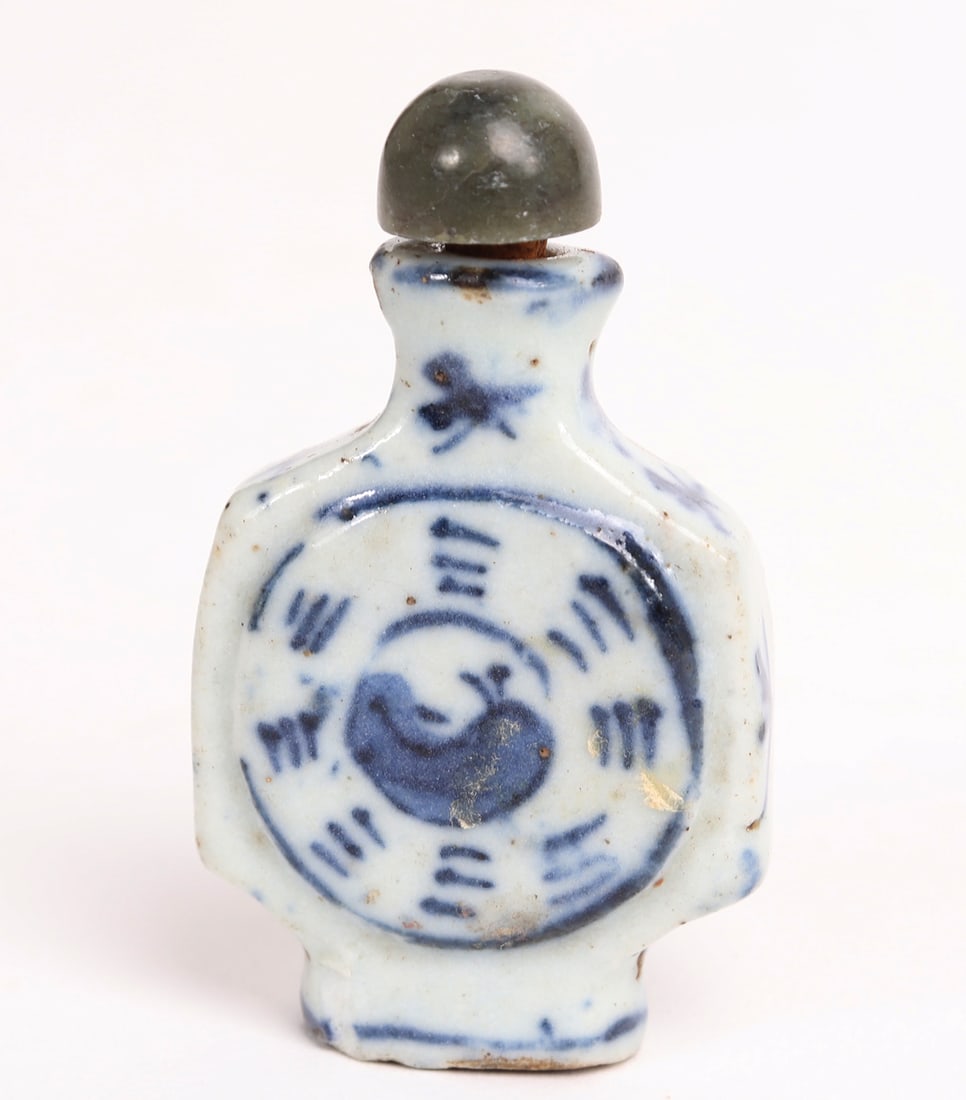 Antique Blue and White Snuff Bottle: Rare miniature blue and white porcelain snuff bottle with a jade stopper. Uniquely squared into an almost canteen like shape, the bottle is painted with star bursts to shoulders, and yin-yang to front