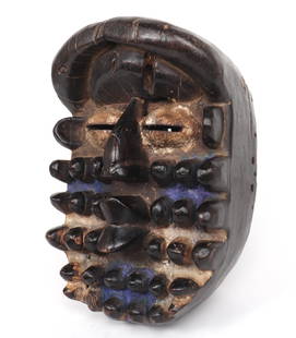 Large African Wobe or We Mask: African, Ivory Coast wobe or we mask hand carved from a single large piece of wood, this mask has a bright blue pigment on both cheeks as well as his chin. Expressing a 'kiss me' like face, he also ha