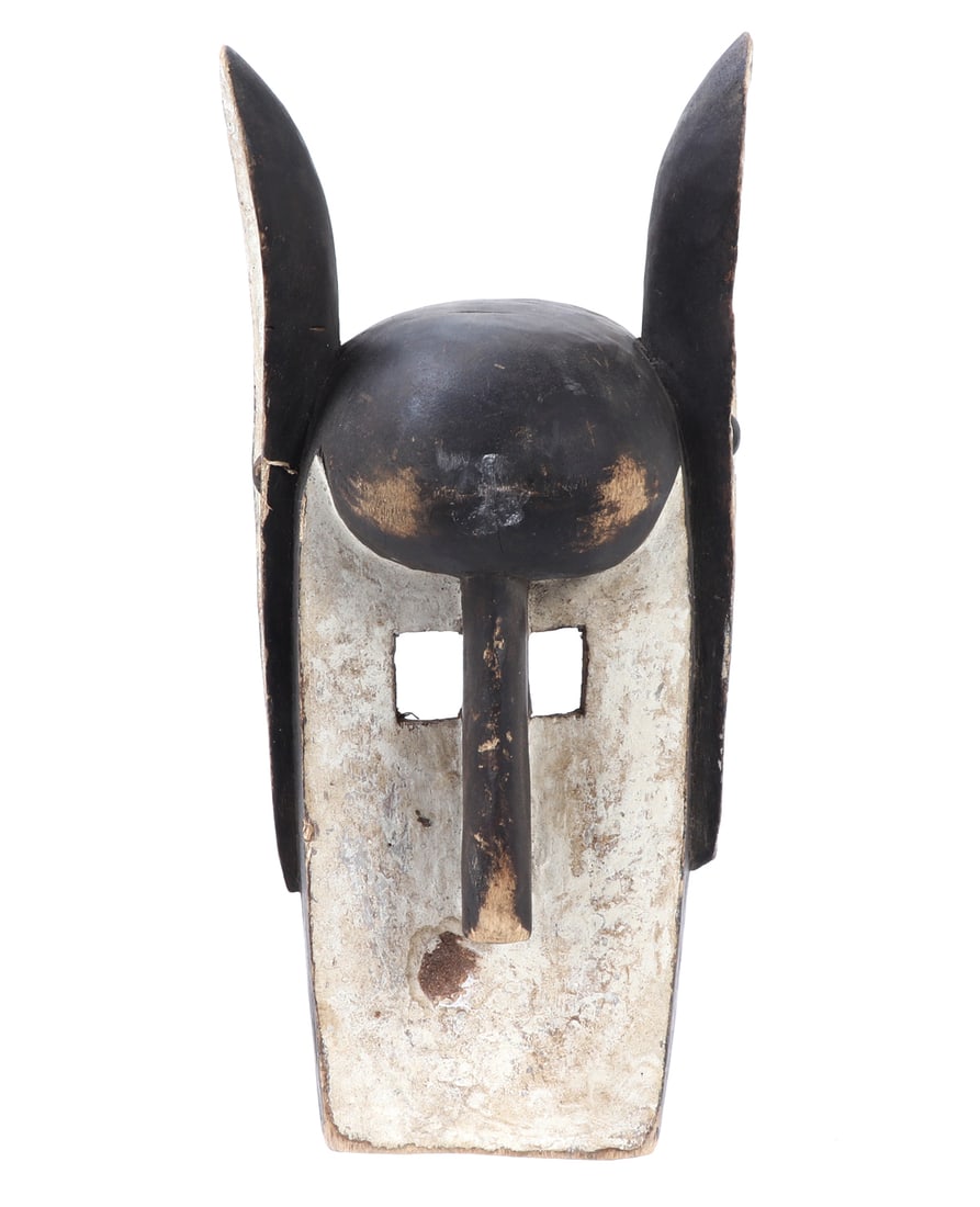Wood Carved Dogon Dyommo Mask: African wood carved Dogon Dyommo mask. Classic box shape form with elongated rabbit style ears. Squared pierced open eyes. Accented throughout with black and white pigment. Size 13 3/4" H x 6 1/4" W C