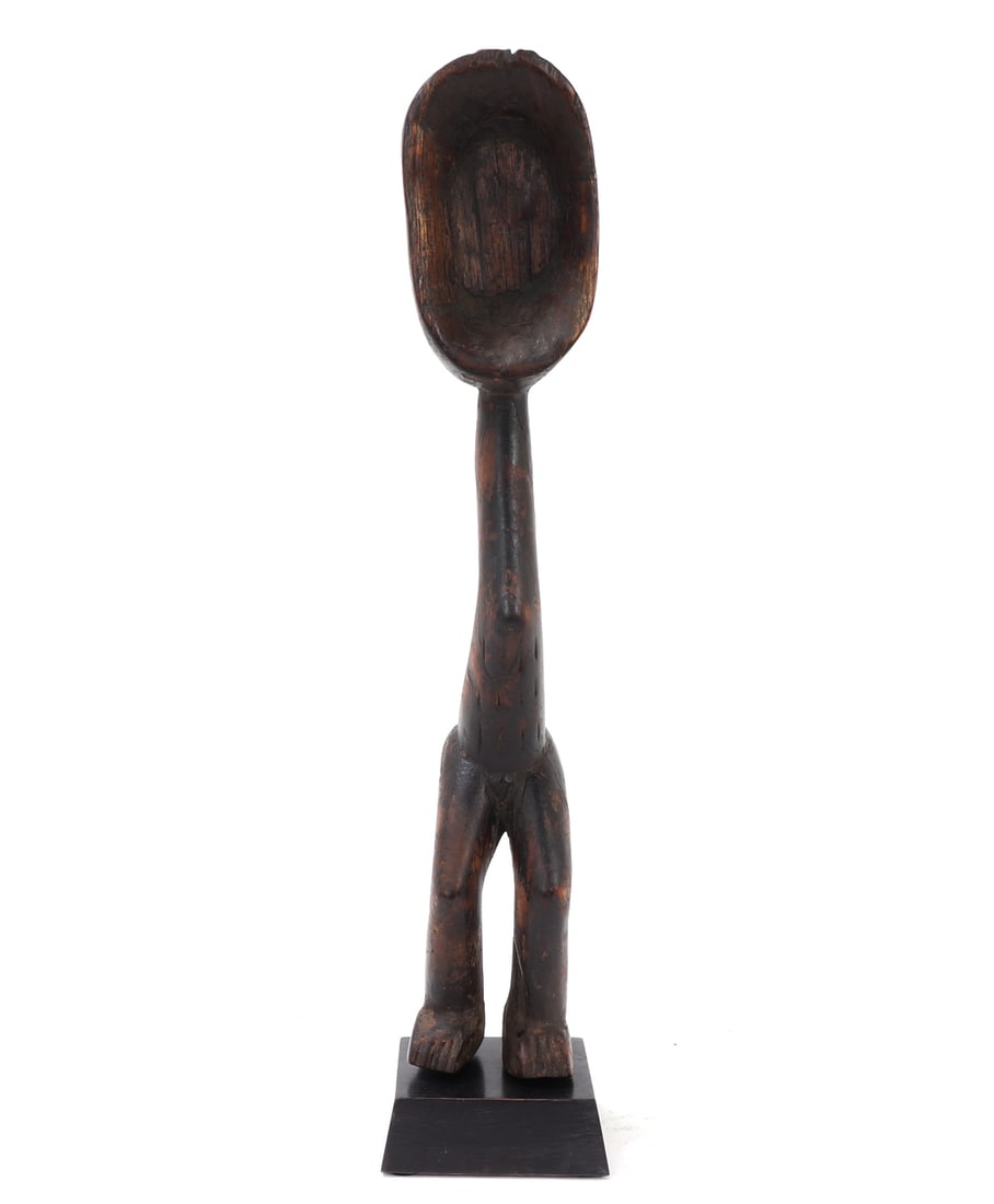 African Wood Carved Spoon on Stand, Dan: Finely carved African wood spoon. Bowl of the spoon acts as the head, leading to a slender body with a large rear-end in classic form, standing on a custom base. Finely detailed braided hair detail to