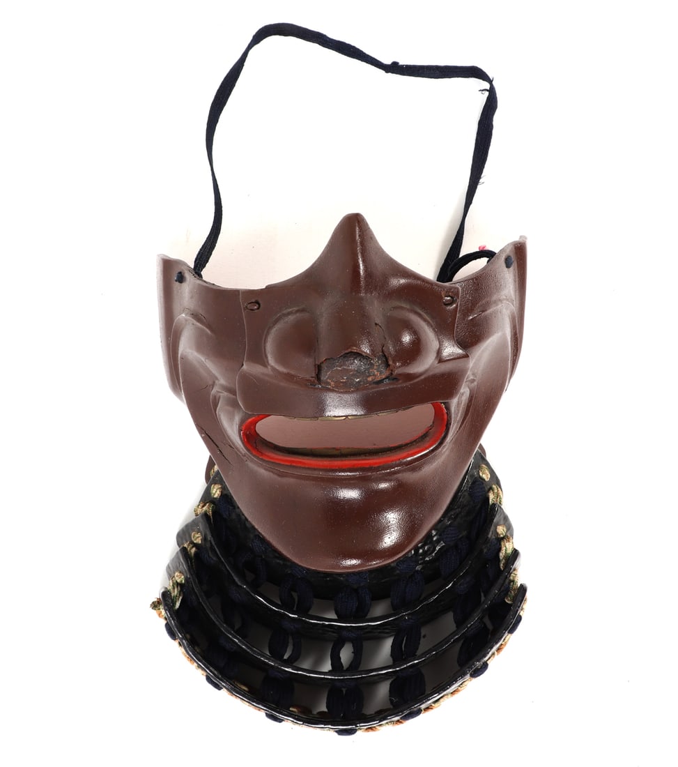 Japanese Armor Menpo Face Mask: Japanese armour Menpo face mask with a serene yet formidable expression typical of traditional samurai armor. The integral throat guard is secured with cotton-weave cord . Size Mask 5 1/4" H, Neck 9"