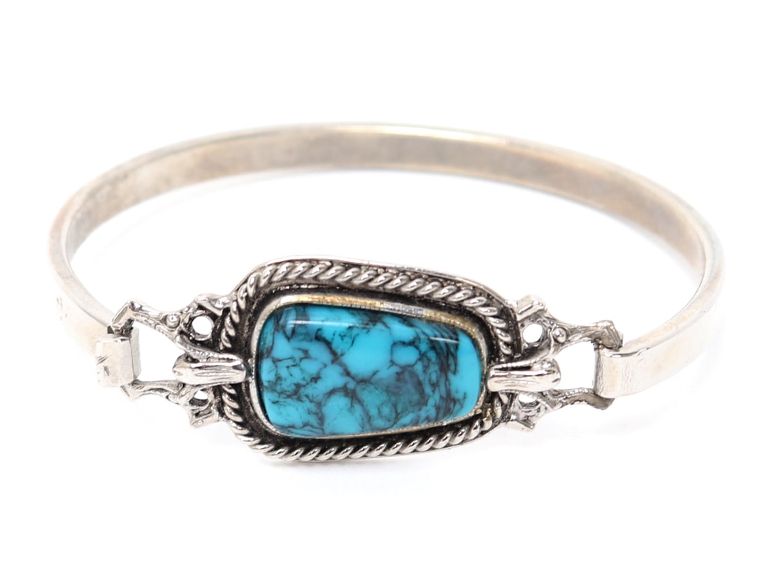 Silver & Turquoise Bangle: Native American silver and turquoise silver bangle with a hinged clasp. Bright blue polished oblong turquoise segment, surrounded by a lovely rope bezel. Size 2 1/2" W x 2" H, 18 grams Ex-Southwest Co