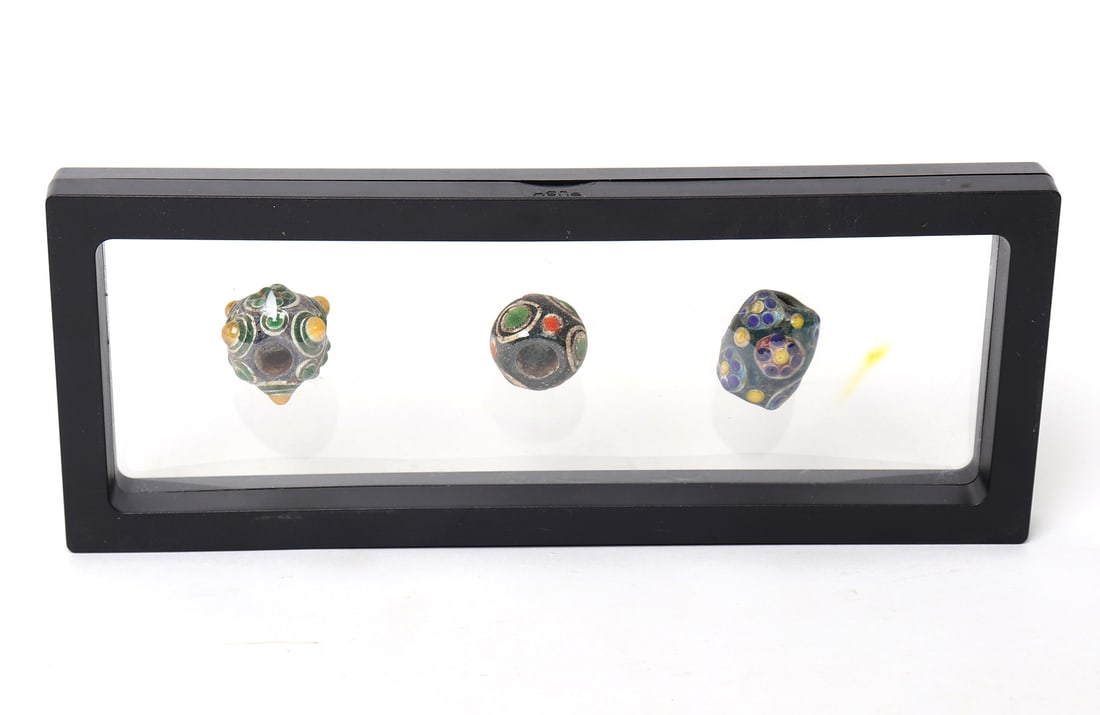 Trio of Chinese Glazed Beads: Group of three Chinese glazed beads, each varying in shape and color combination throughout. Preserved in a shrink wrap frame. Size of frame 9" W x 3 1/2" H, each bead approximately 1" H