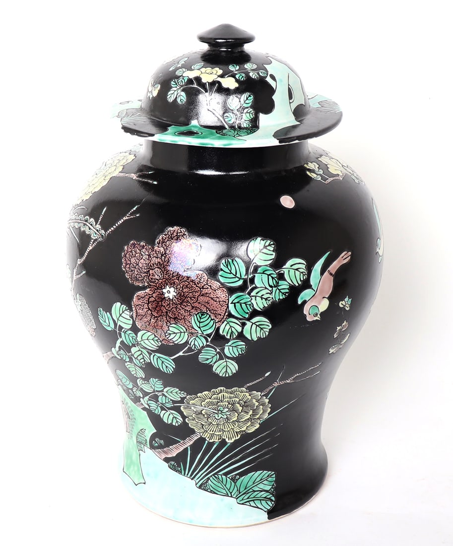 Chinese Black Glazed Ginger Jar: Chinese porcelain ginger jar with lid, black glaze background with bright yellow, pink and green throughout. Flowers in bloom and birds in flight among bamboo and trees. Seal mark to the base. Size