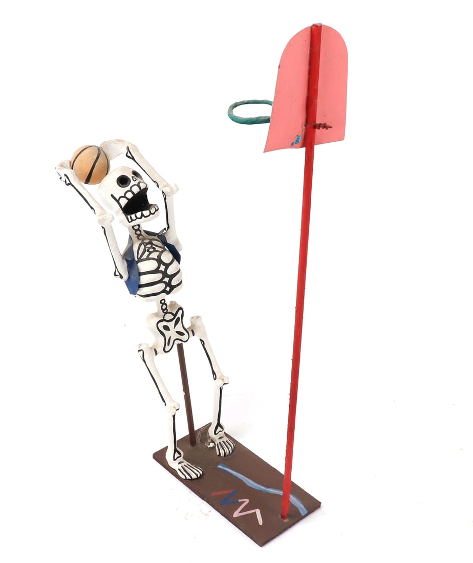 Paper Mache Death Playing Basketball: Mexican made paper mache skeleton playing basketball launching towards the basket for a slam dunk. He wears a blue vest and is mounted to a wood base with brightly painted basket. Size 21" L x 4" W x