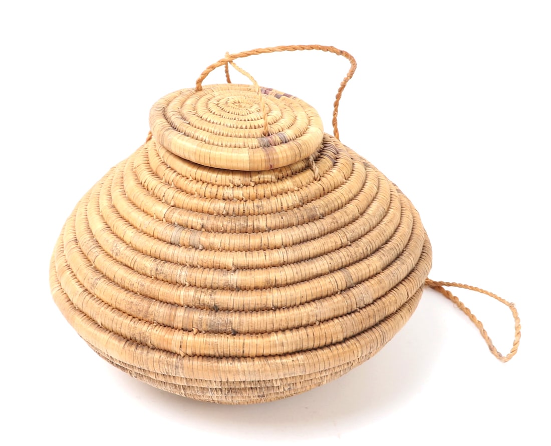 Woven Coiled Hanging Basket: Intricately woven and crafted coiled basket with lid and hanging strand. Native American style weaving with remnants of faded pigment to the surface. Size 9" L x 9" W x 5" H, weight 371g