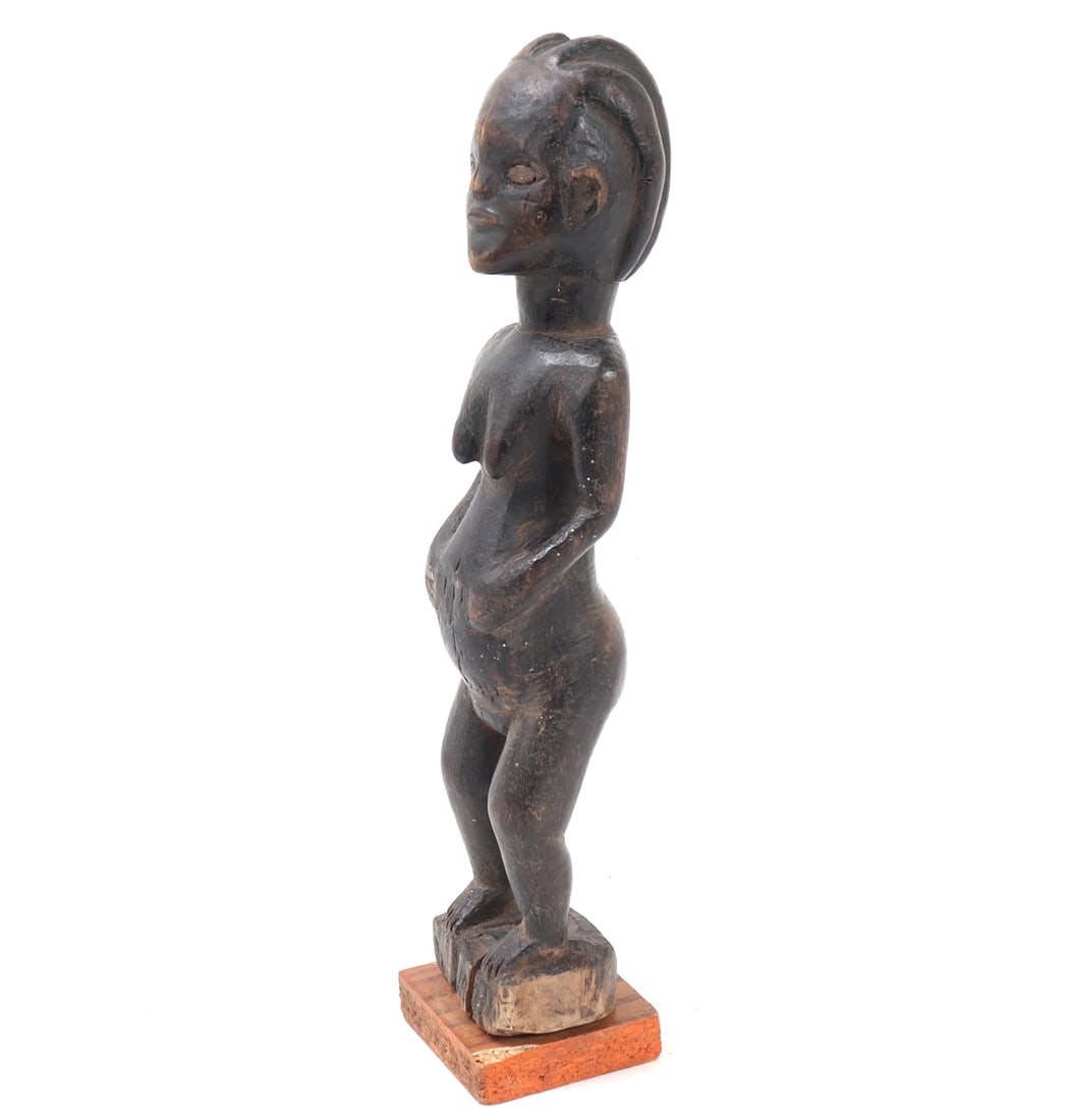 African Baule Wooden Figure: Africa, Ivory Coast. Carved wooden figure from the Baule people of the Ivory Coast. Carved from a hardwood, the dark wood exhibits lighten shades from wear and age creating an attractive patina. Two
