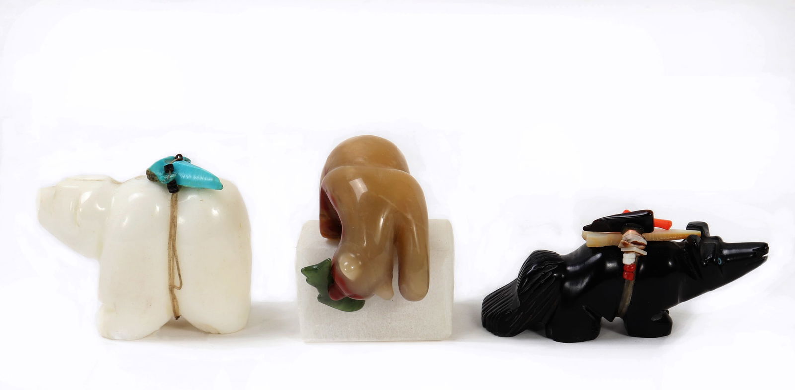 Three Native American Stone Fetish Animal Carvings: Three wonderfully carved and detailed animal fetish animals, carved from various types of stone throughout. A white polar bear with turquoise on his back, a brown bear snags a fish in a warm caramel