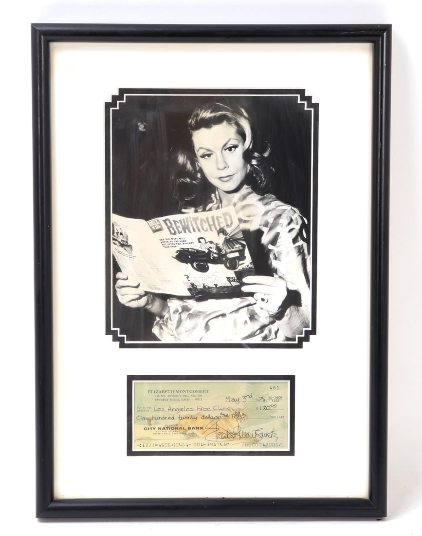 Elizabeth Montgomery Photo & Bank Check: Framed photo of Elizabeth Montgomery in black and white while she reads a magazine. Also includes a bank check signed by the actress Elizabeth Montgomery, who starred as Samantha Stephens in the TV