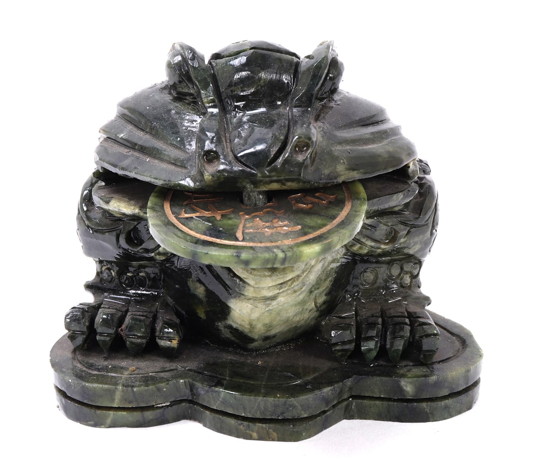 Chinese Jade Style Money Toad: Chinese jade style stone carved money frog with a piece of free moving currency in the toad or frog mouth. Depicted seating on a custom stone base likely a lily pad or stone. Incised detailing