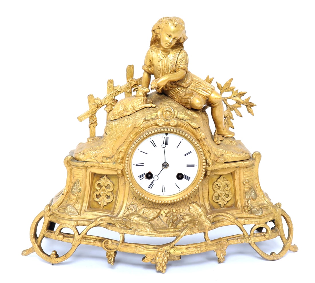 French Gilt Bronze Mantle Clock, 19th c.: French gilt bronze mantle clock with a gentile scene of a girl resting with a lamb. The base with openwork and scrolling grape vines bearing fruit. Size 13" W x 11 1/2" HEx-Private USA collection
