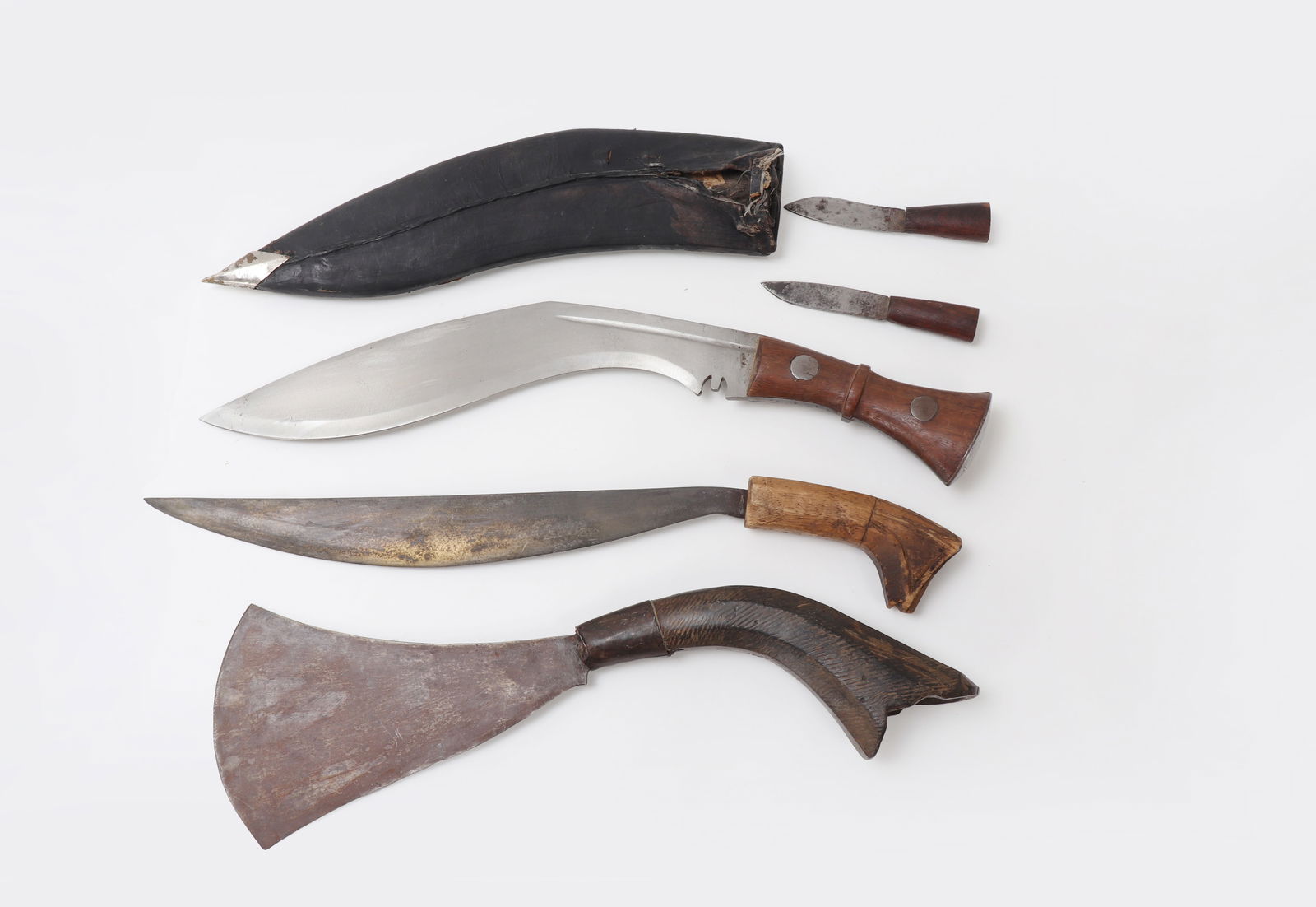 Collection of Philippine Weapons: Great assortment of Philippines armaments including a Kukri with accessory knives in original sheath. Center Talibong machete short sword with carved wood handle and single edge blade terminating to a
