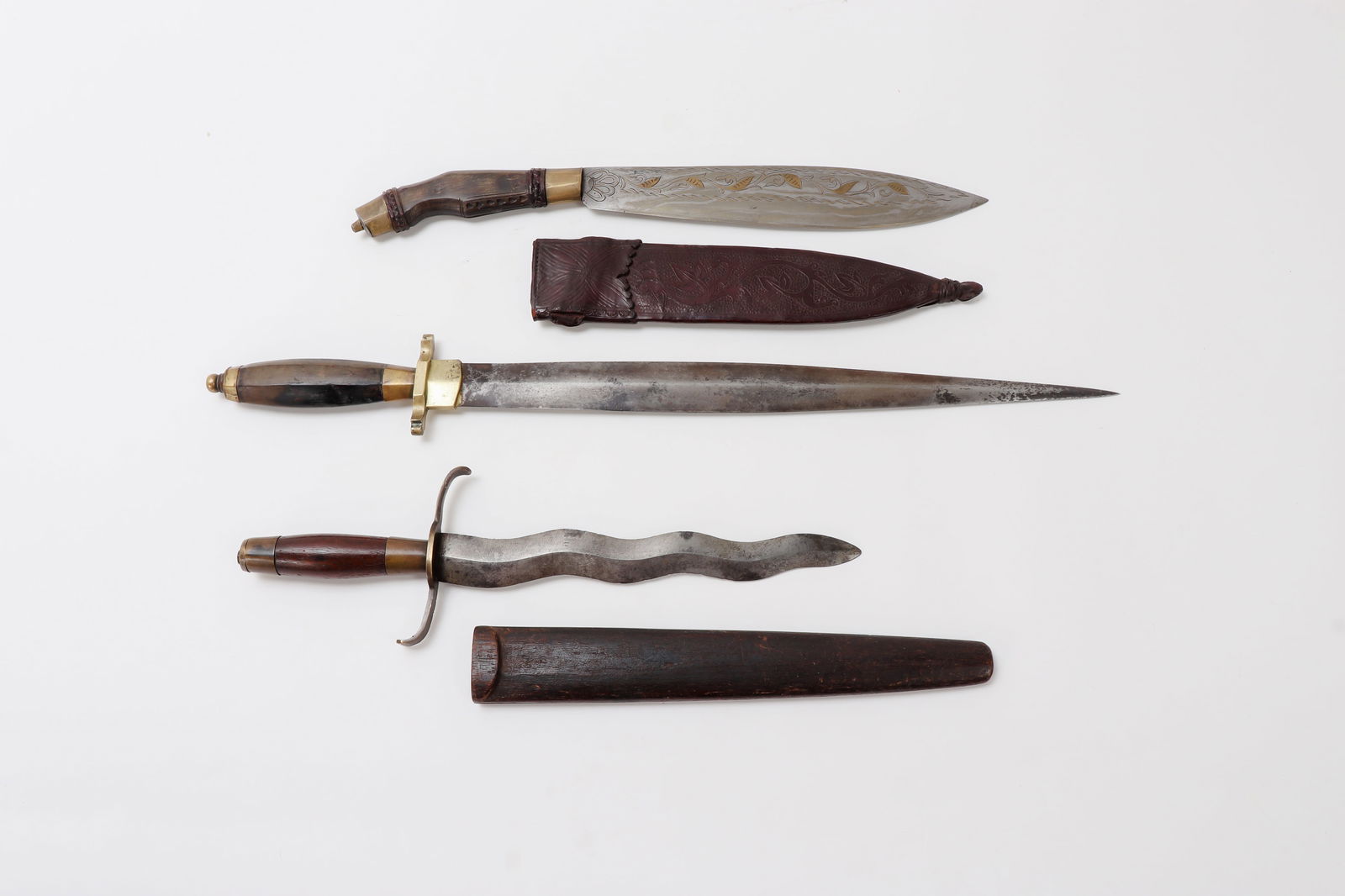 Trio of Superb Luzon Daggers: (Top) Superb Luzon Bolo Dagger with fantastic floral pattern brass engraved and inlaid blade. Grip in carabao horn carved with geometric motifs and patterns. Fine brass fittings. Leather scabbard