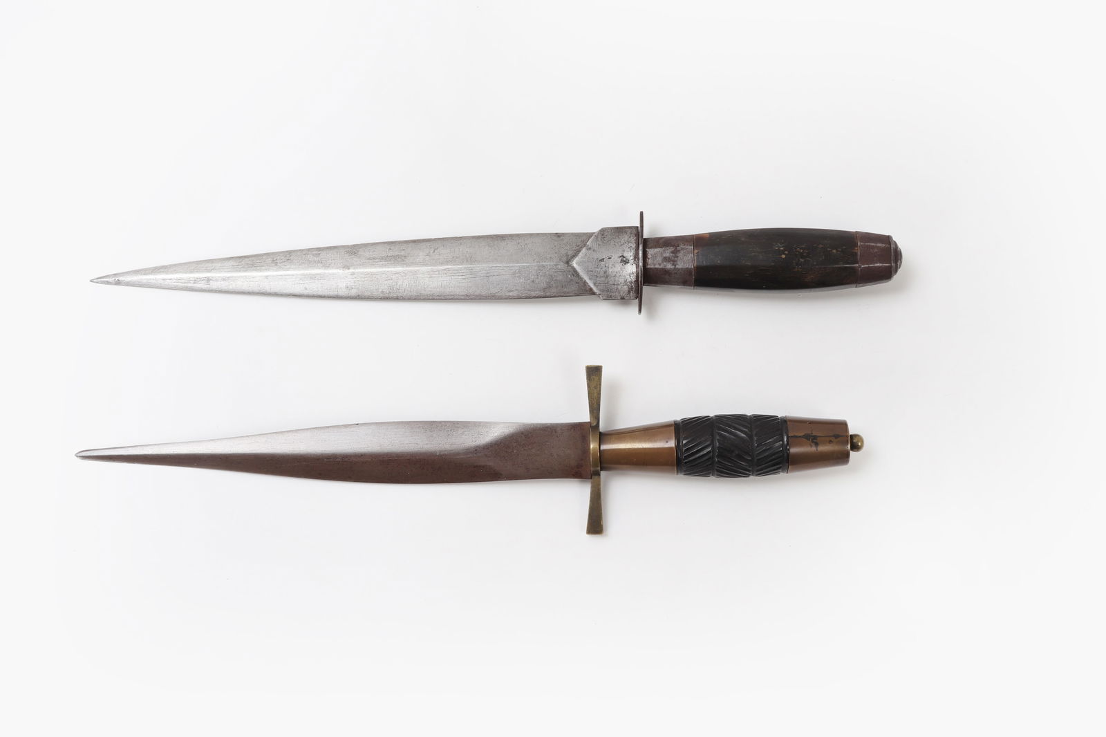 (2) Luzon Daggers: Excellent set of Spanish Colonial style Luzon Daggers each with carabao horn grips. Lower most example in brass circa 1900-1930. Upper example circa late 19th century. 14"