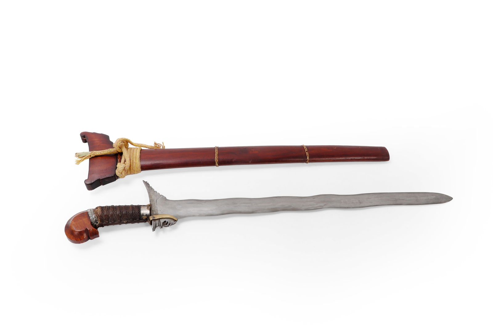 Moro Kris Sword and Scabbard: Moro Kris sword with rare floral carved wood pommel and silver mounts. Maguindanao peoples with intricately interwoven and twisted fiber roped grip. Double edged 9-wave blade with brass asang. Overall