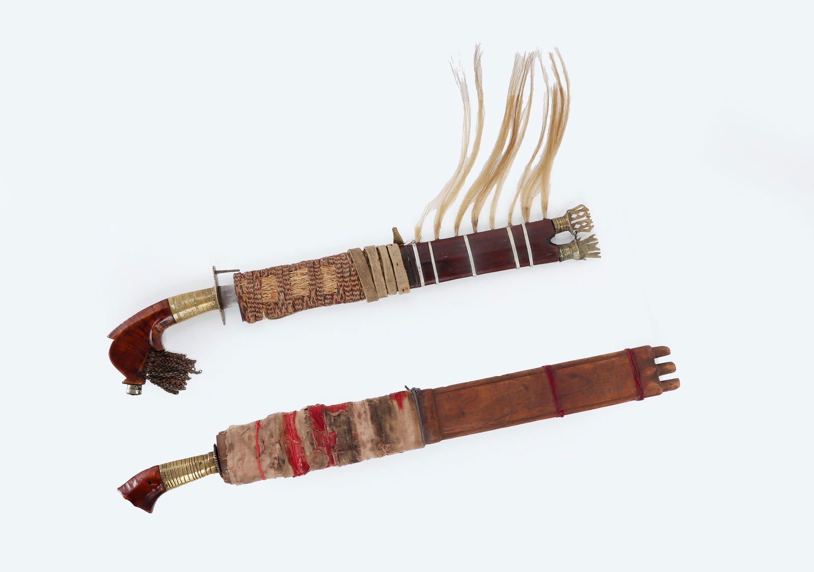 Moro Lumad Tribes Barong Swords: Mindanao Lumad Tribes Barong swords each with scabbard and trade blades. Bagobo kris sword with wavy double edge blade and shallow fuller with talismanic marks. Scabbard with red & white textile wrapp