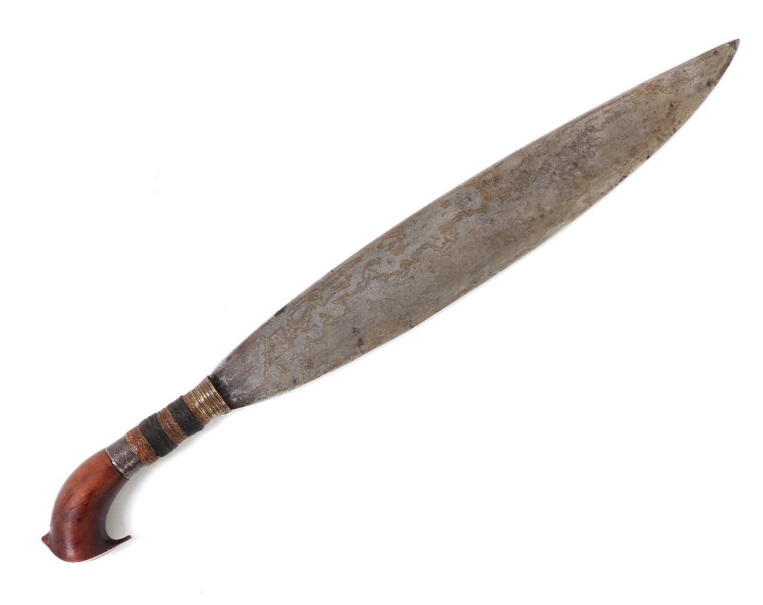 Philippines Moro Barong Sword: Filipino Moro barong sword with brass cuff, bands of rattan wrap and sliver base to handle. Wood pommel with thin beak and small crest. Typical leaf shaped single edged blade. Size 23 1/2" L, blade17