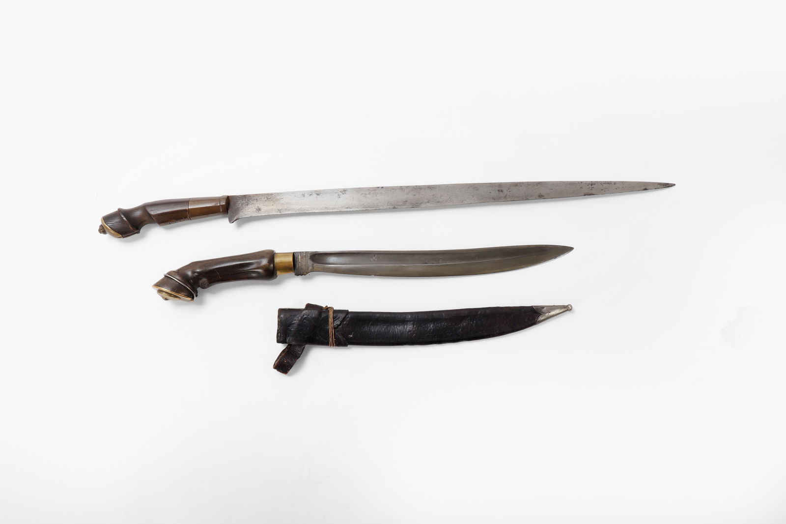 Pair of Horsehoof Daggers: Philippines, Luzon Hoof handle dagger and sword set. Dagger with fine brass mounts over a horn carved relief hoof handle with single silver band, including original scabbard. Blade a single edge with