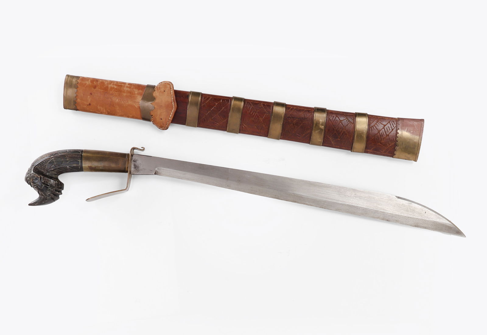 Talibong Bicol Deity Sword & Scabbard: Philippines, Talibong Bicol Deity left handed sword and scabbard, circa first quarter of the 20th century. Zoomorphic carved and engraved horn handle with brass sleeve to base and brass guard. Blade a