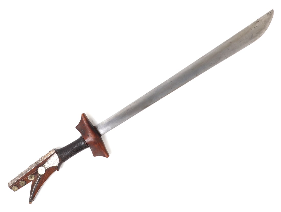 Rare Silver Embellished Kampilan Sword: Excellent example of a very finely embellished Kampilan sword. Typical bifurcated fish head handle covered with panels of scrolling engraved silver pinned with copper over the wood surface.