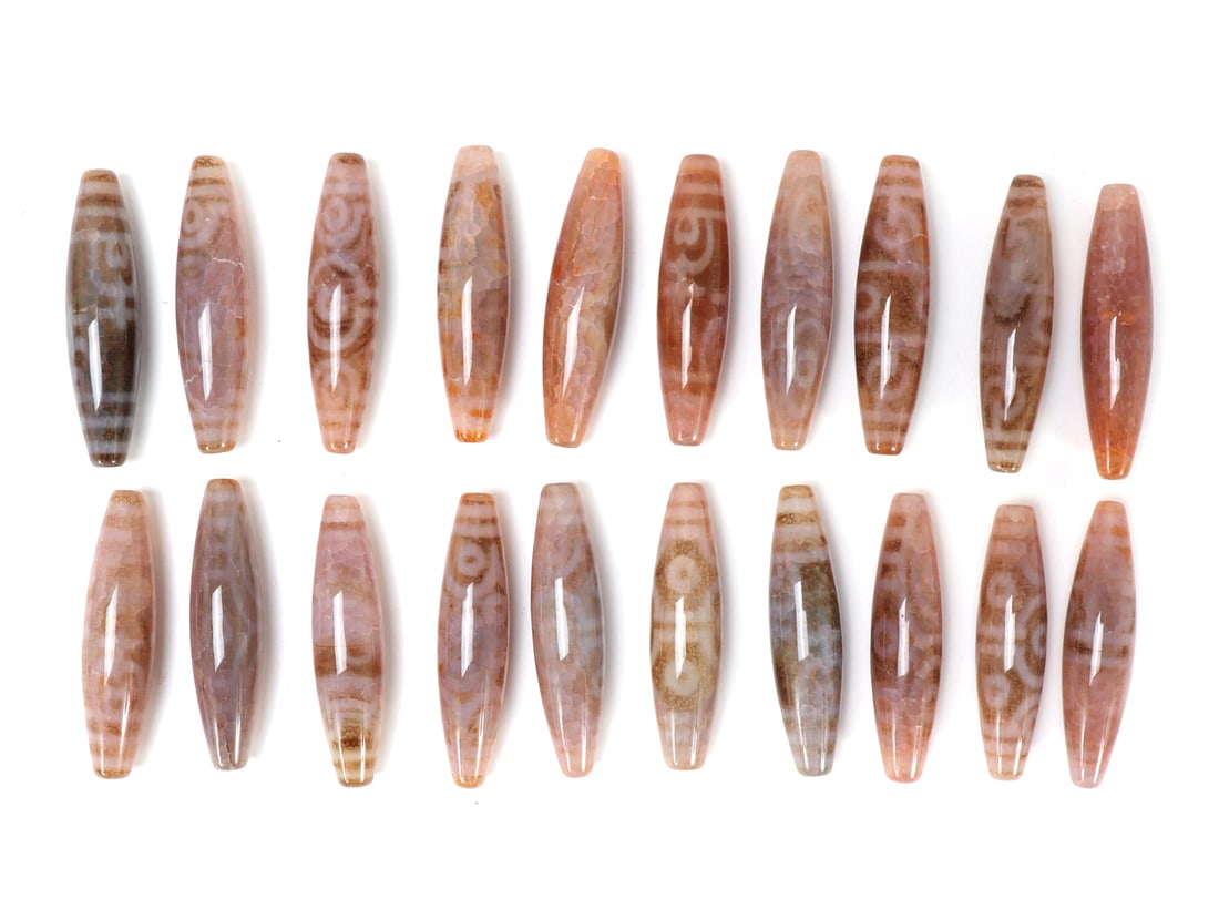 Twenty Lovely Tibetan Dzi Beads: Wonderful collection of twenty various colored Tibetan stone Dzi beads. Some in dark earth tones, others in a pretty coral pink color. Traditional eye formations throughout each bead. Size of each