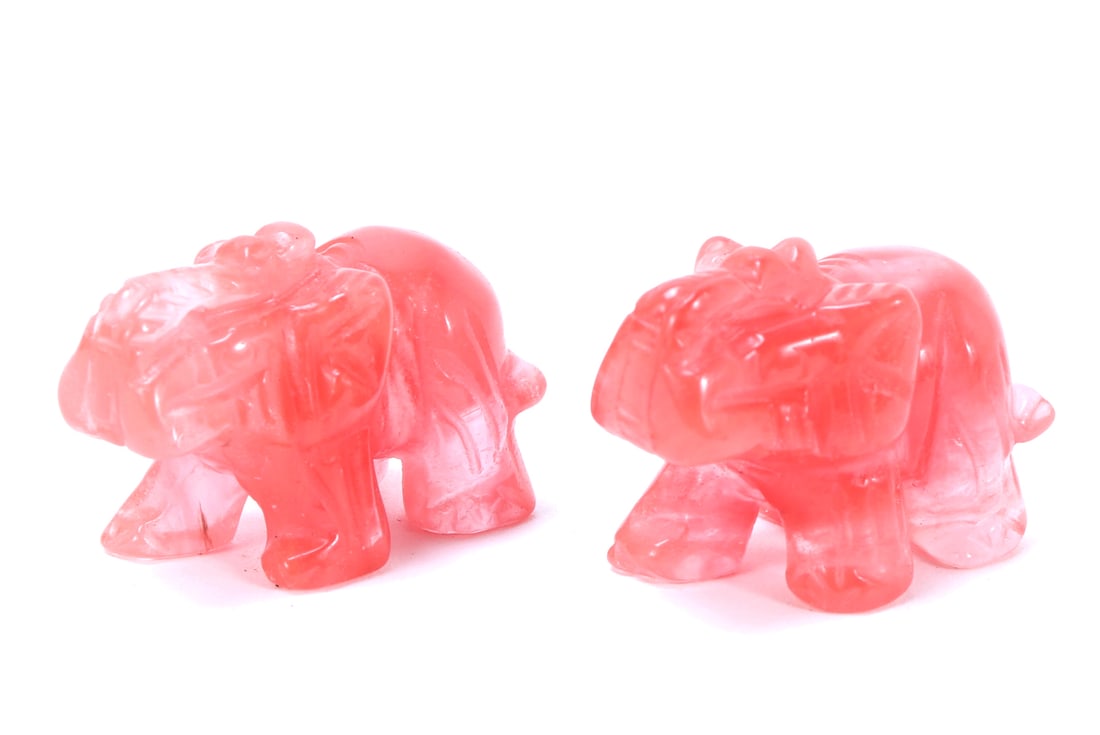 Pair of Adorable Rose Crystal Quartz Elephants: Matched pair of hand carved rose crystal quartz elephants, each beautifully bright pink with areas of crystal clear translucency. Trunks raided high in the sky as a sign of happiness and good luck.