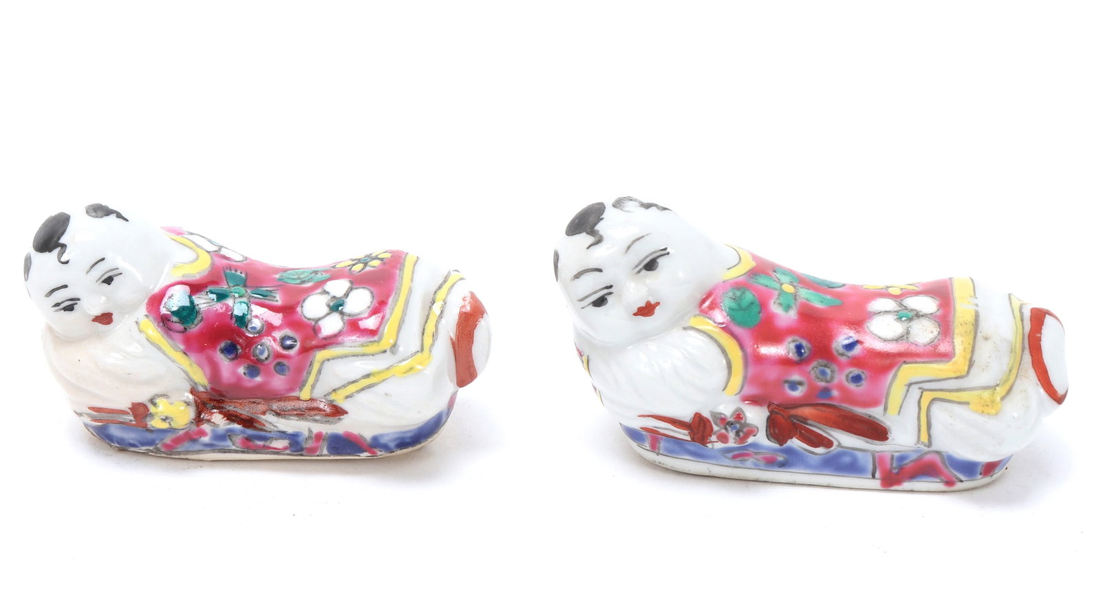 Pair of Chinese Brush Rests: Pair of Chinese porcelain brush rests with pink robes with floral decoration throughout. Baby monks are depicted on their bellies with happy smiling faces. Size 2 3/8" L