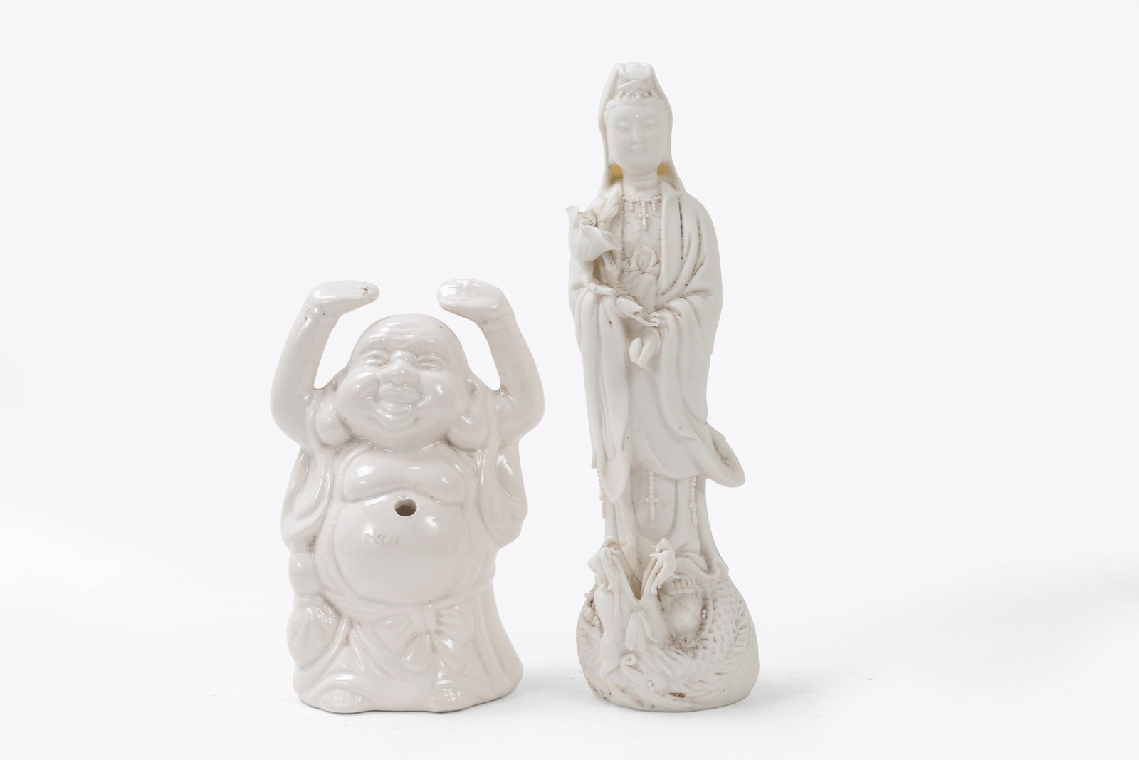 Chinese Blanc De Chine Porcelain Figures: Buddha and Guanyin, each expertly crafted in the 20th century. The tallest, standing at 11 inches, showcases the serene grace of Guanyin, holding a lotus and adorned with flowing robes. The second