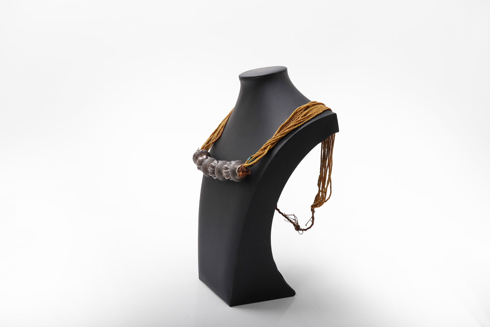 Antique Nepali Beaded and Silver Wedding Necklace: Nepal, 19th to early 20th century. Composed of multiple strands of small ochre seed beads, joined at the front by a series of large repousse silver elements of lobed form. The strands gathered at the