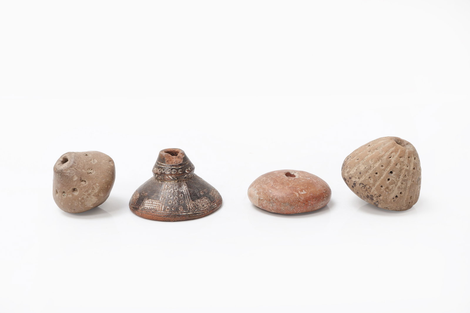Collection of Large Terracotta Spindle Whorls: Collection of four terracotta spindle whorls featuring one Pre-Columbian small-form terracotta spindle whorls from the Quimbaya culture 1000BCE - 1200CE (second from left). Remaining three ancient