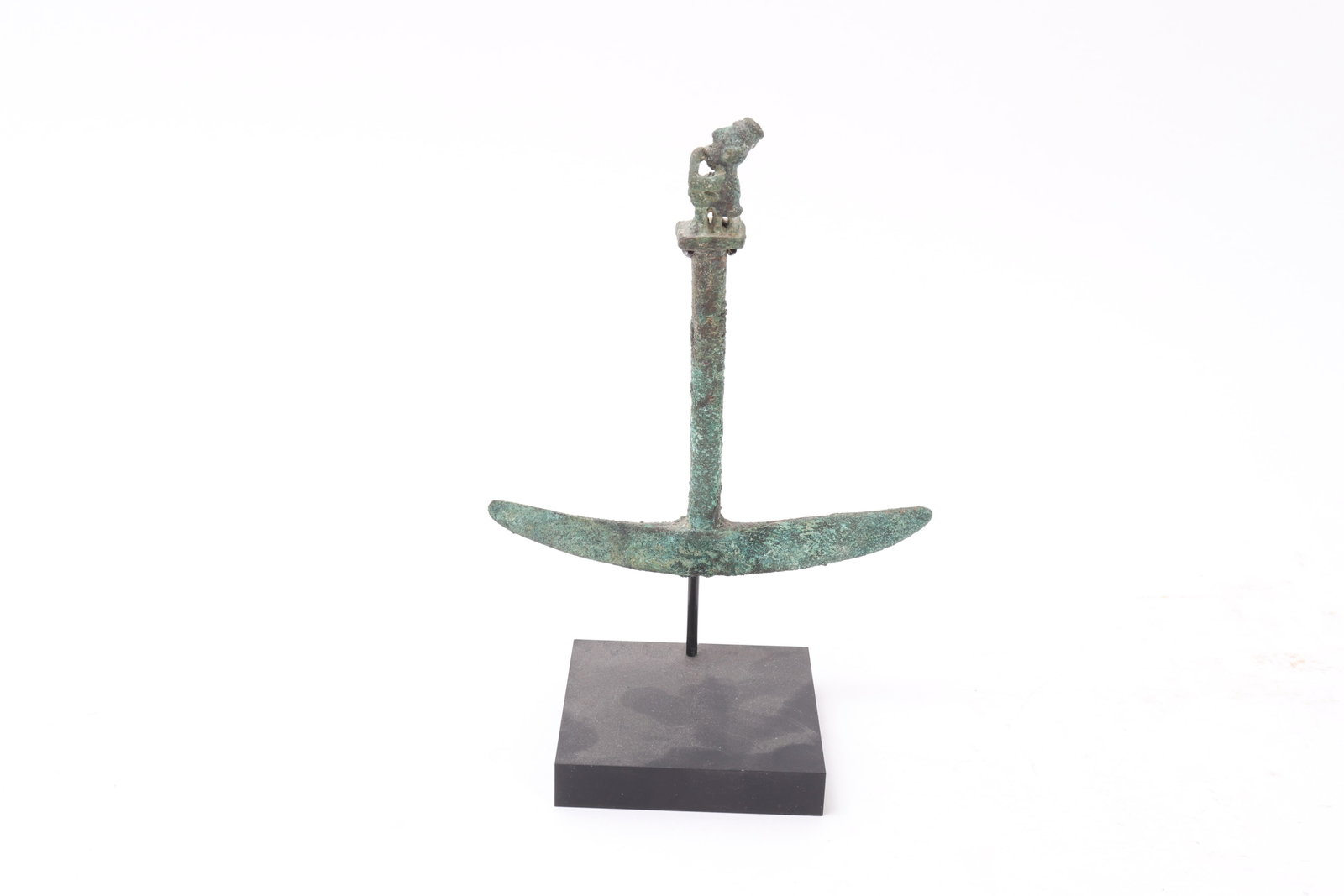 Pre-Columbian Peruvian Bronze Ceremonial Knife: Pre-Columbian, probably Peru, circa 500 BCE - 500 CE. Cast copper alloy ceremonial knife of unusual anchor-like form, the broad crescentic blade rising to a tapering central shaft surmounted by a smal