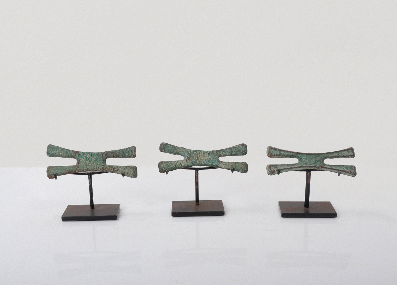 Three Katanga-Style Copper Cross Forms, Mounted: Democratic Republic of the Congo (Katanga Region)20th Century A set of three cast copper cross forms, presented on later custom stands. Each is modeled after traditional Katanga cross currency types