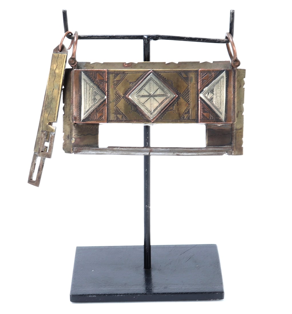 Traditional Tuareg Handcrafted Lock: These locks were historically used by Tuareg woman to protect family possesions. They feature geometric patterns and multi- step lock system. Size 4 1/2" W, 7 1/4" H on included stand.
