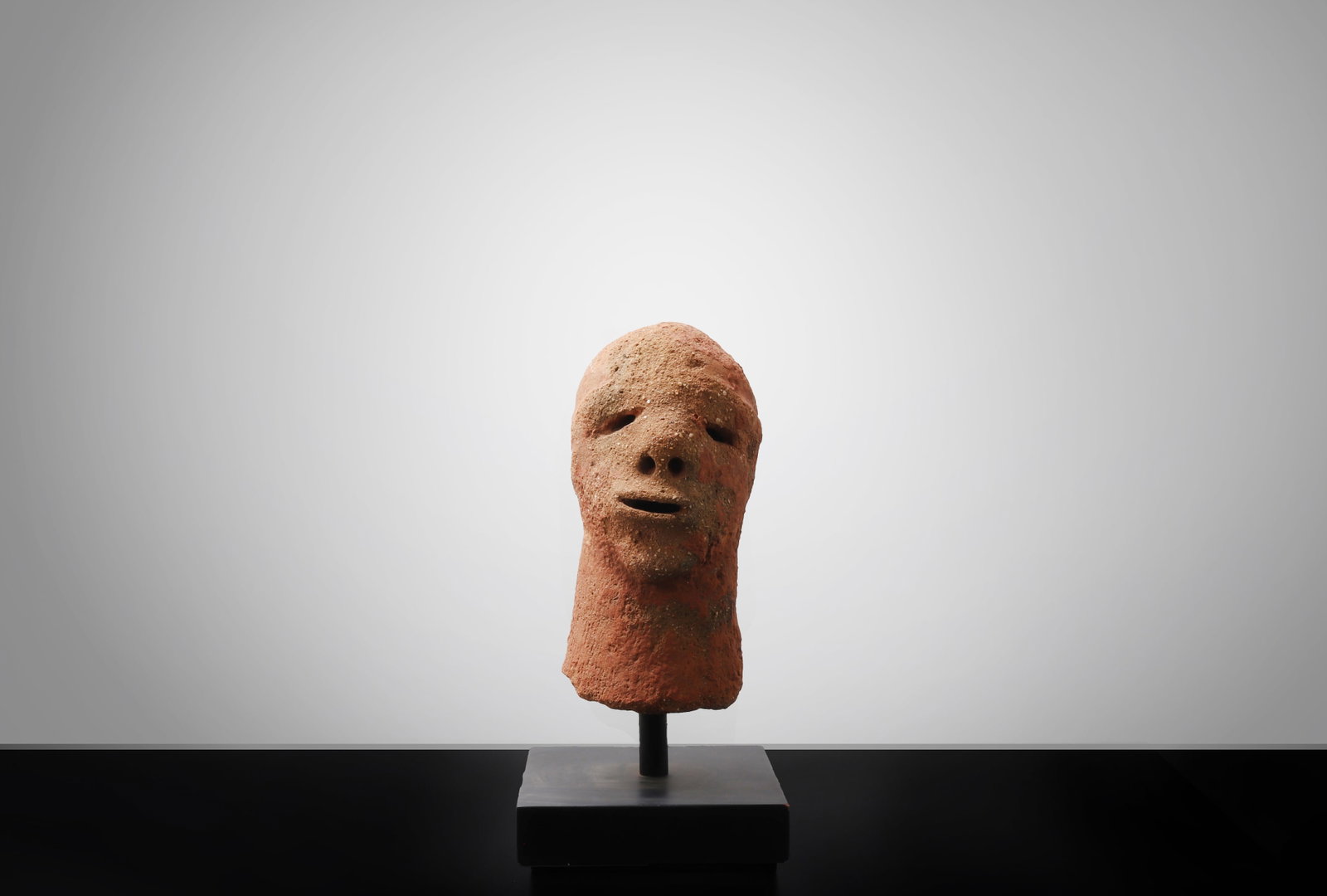 West African Nok-Style Terracotta Head, Mounted: West Africa, likely Nigeria, Nok-style terracotta sculpture possibly of the 500 BCE?200 CE period. A striking terracotta head fragment of elongated form, sensitively modeled with a high rounded