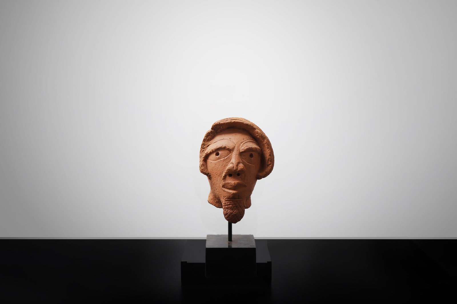 Nok-Style Terracotta Head: West Africa, probably Nigeria, Nok culture or later in the Nok style, probably circa 500 BCE?200 CE or later. Terracotta head modeled with a rounded face, deeply recessed circular eyes, a short