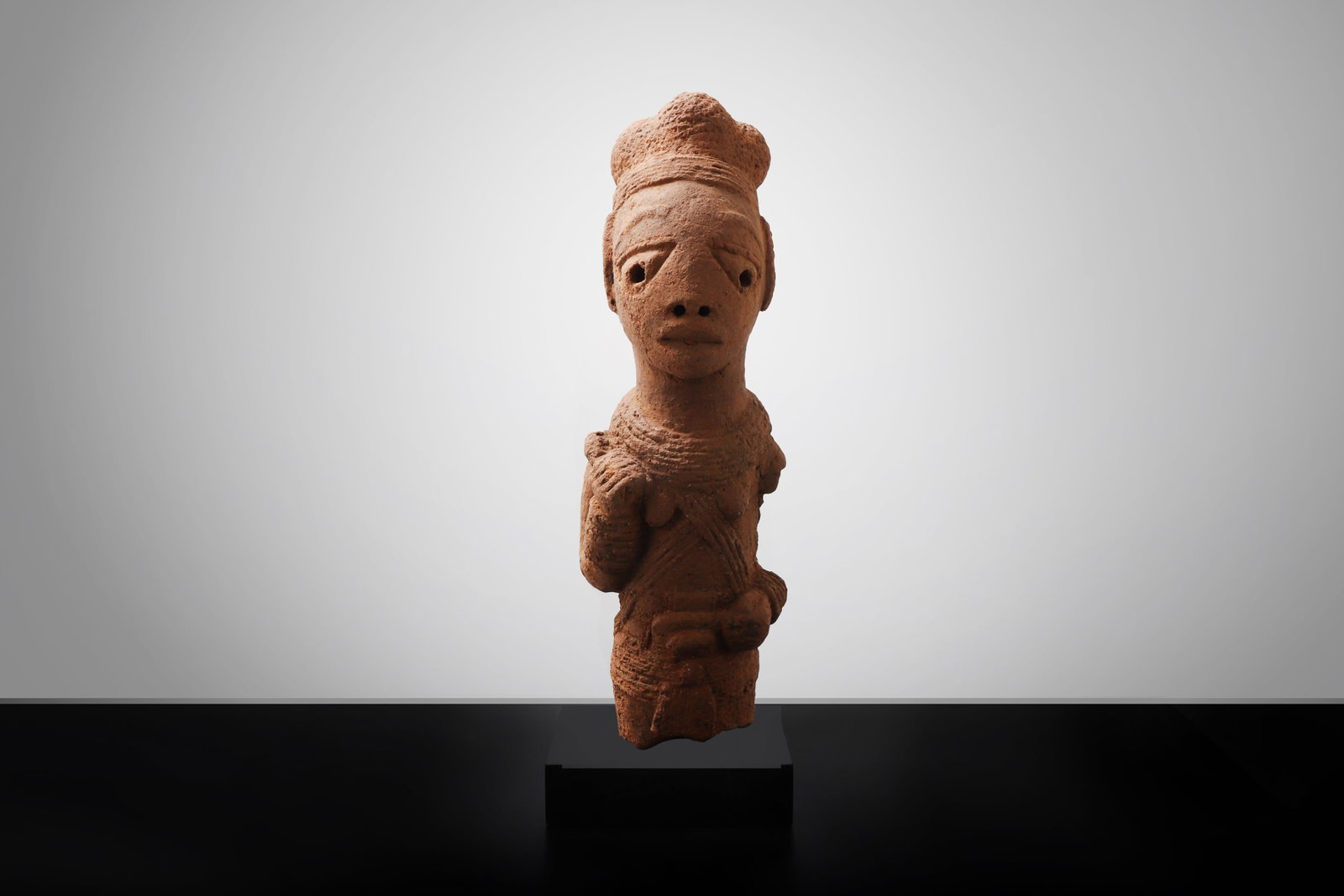Nok Terracotta Standing Figure: Nigeria, Nok culture, possibly ca. 500 BCE - 200 CE. A large terracotta standing figure modeled in reddish-brown earthenware, shown frontally with an elongated head, high coiffure or cap-like headdres