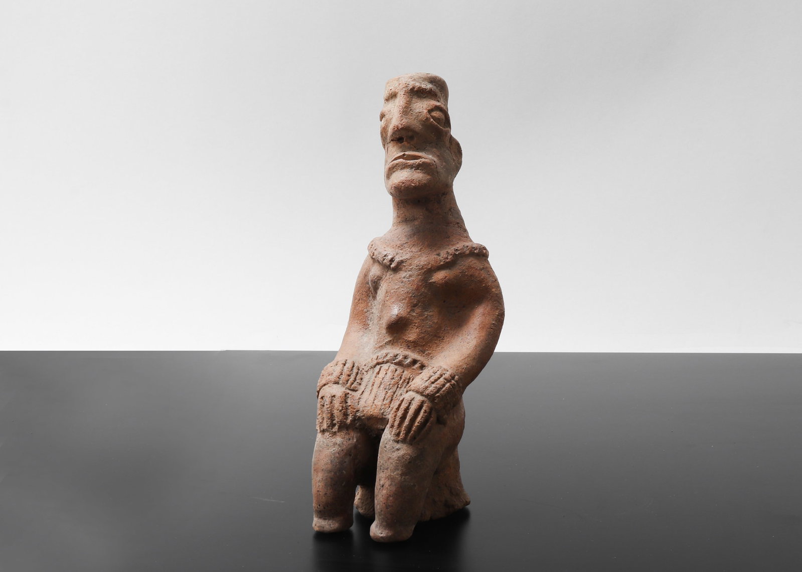 Koma Builsa Seated Terracotta Ancient Figure: Terracotta molded statue depicts an anthromorphic figure in a seated position. Probably Koma in Northern Ghana style of the (13th to 16th century CE). Seated with stocky arms and hands resting on the