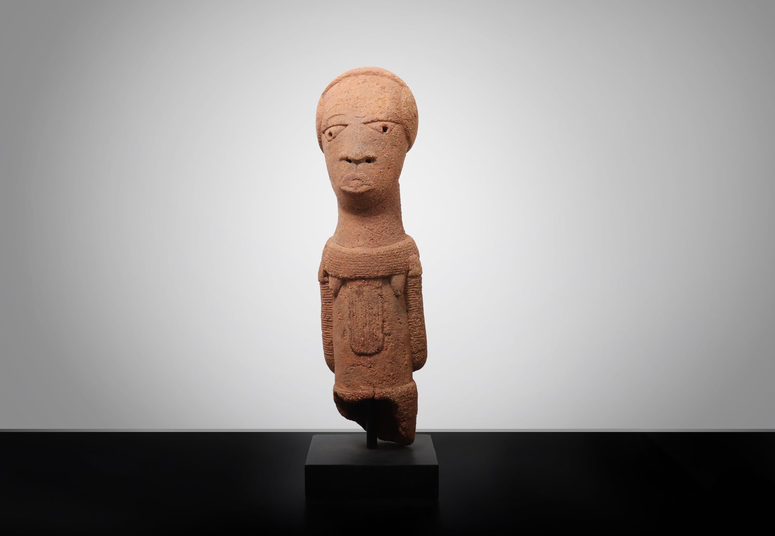 Nok Terracotta Male Figure: Nigeria, Nok Culture, circa 500 BCE-200 CE. A terracotta male figure with elongated cylindrical body, rounded base, and highly stylized facial features characteristic of Nok sculptural tradition. The 