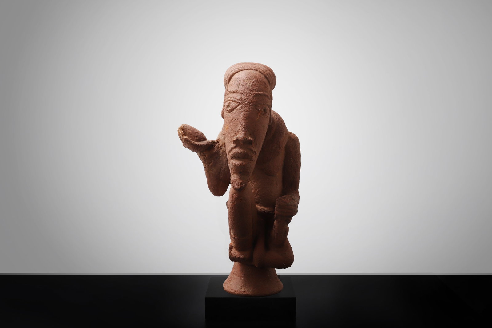 Nok Terracotta Male Figure: Africa, Possibly 1000 BCE - 300 CE . Terracotta figure shown in a compact kneeling posture, the elongated head with sharply projecting nose and deeply set features lending the work a particularly expr